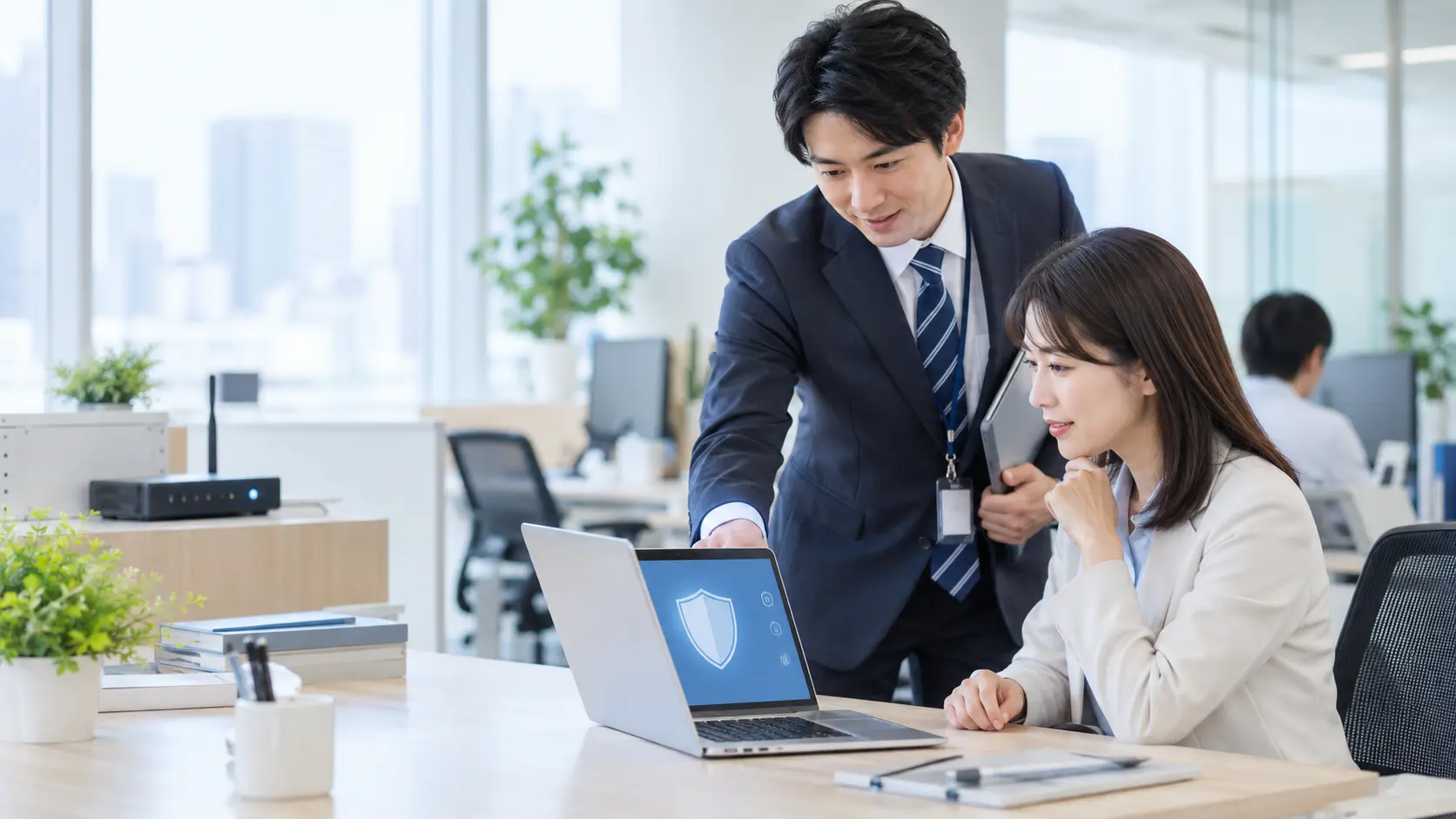 明るいオフィスで担当者と利用者がパソコンの安全確認を行う様子
